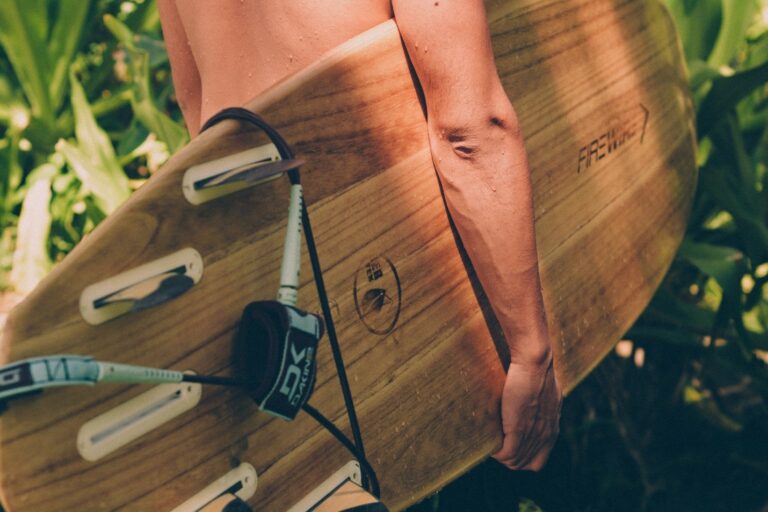Surfer carries board with fins and leash